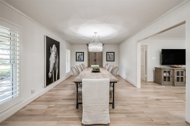 dining space with light wood-type flooring, ornamental molding, and a chandelier