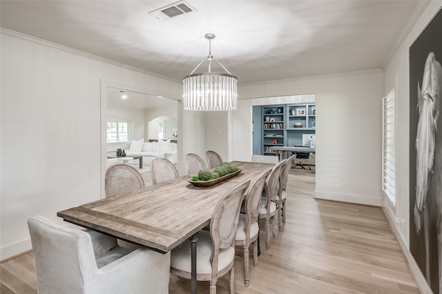 dining space featuring light wood-type flooring, ornamental molding, and a chandelier