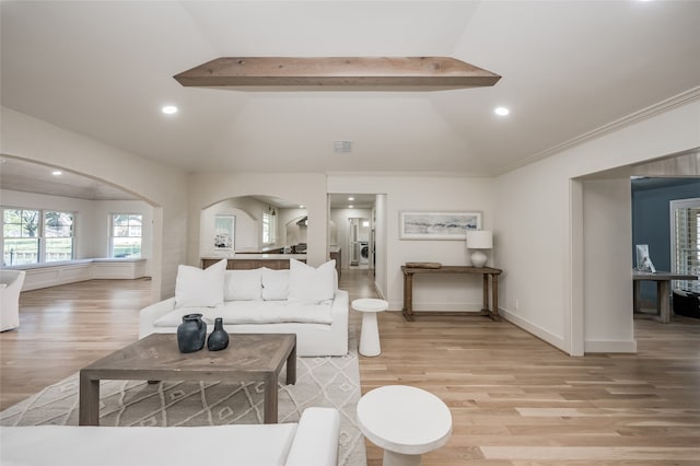 living room with vaulted ceiling with beams and light hardwood / wood-style flooring