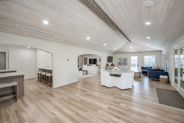 living room featuring vaulted ceiling with beams and light hardwood / wood-style flooring