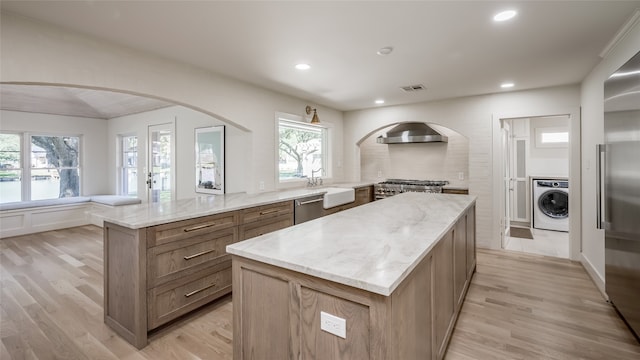 kitchen featuring washer / dryer, a center island, light stone counters, and light hardwood / wood-style floors