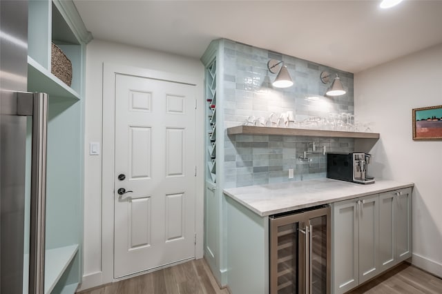 bar with gray cabinetry, backsplash, wine cooler, and light hardwood / wood-style floors