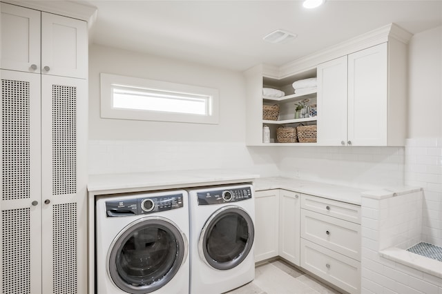 laundry room with independent washer and dryer, light tile floors, and cabinets