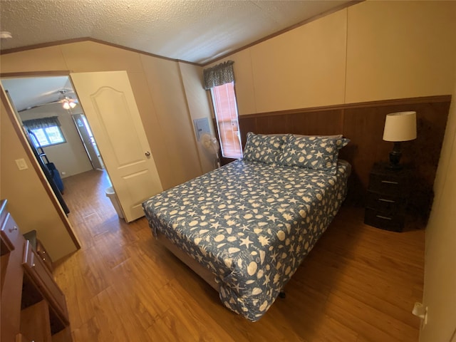 bedroom featuring a textured ceiling, light hardwood / wood-style flooring, and vaulted ceiling