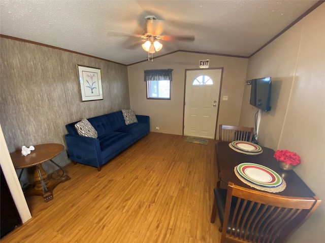 living room featuring ceiling fan, vaulted ceiling, light hardwood / wood-style flooring, and a textured ceiling