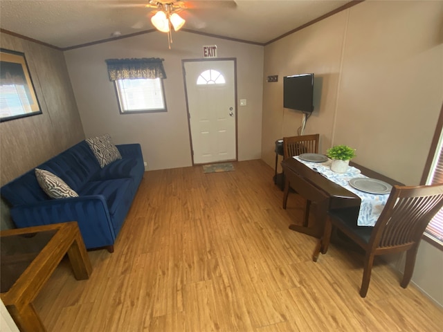 living room featuring ceiling fan, ornamental molding, light wood-type flooring, and vaulted ceiling