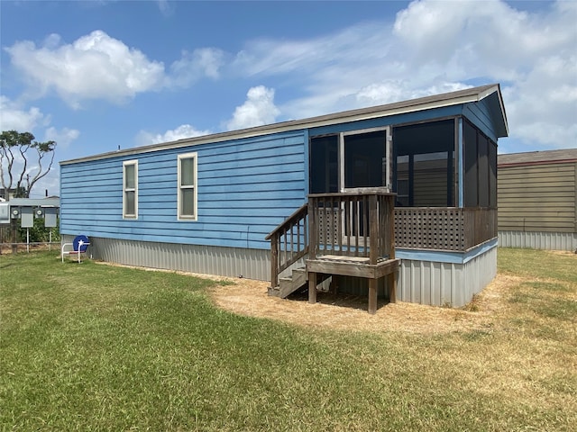 rear view of property featuring a sunroom and a lawn