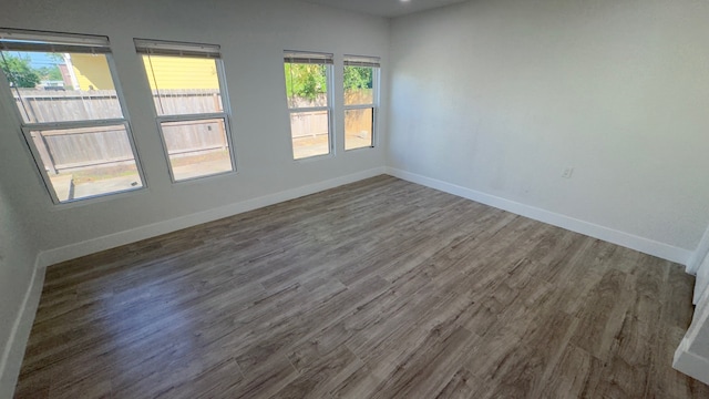 empty room with a healthy amount of sunlight and dark wood-type flooring