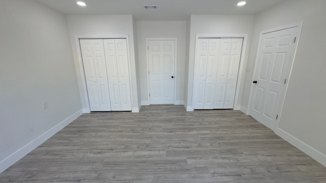 unfurnished bedroom with multiple closets and light hardwood / wood-style flooring