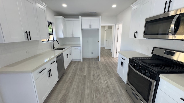 kitchen with backsplash, light wood-type flooring, white cabinetry, and appliances with stainless steel finishes