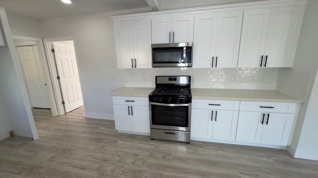 kitchen with stainless steel appliances, light hardwood / wood-style floors, tasteful backsplash, and white cabinetry