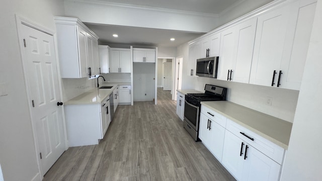 kitchen featuring light hardwood / wood-style flooring, appliances with stainless steel finishes, white cabinets, backsplash, and sink