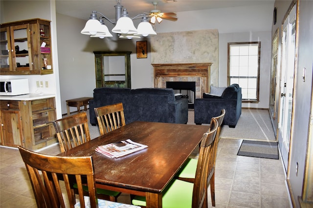 dining area featuring ceiling fan with notable chandelier and light tile patterned flooring