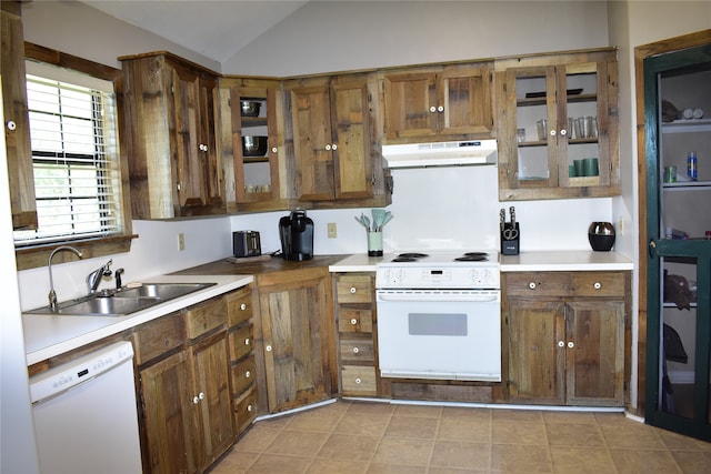 kitchen with lofted ceiling, white appliances, light tile patterned floors, and sink