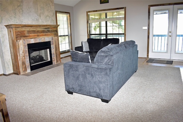 living room featuring lofted ceiling, carpet flooring, a tile fireplace, and french doors