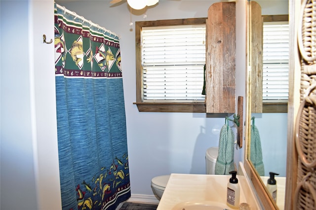 bathroom with a shower with curtain, ceiling fan, toilet, and vanity