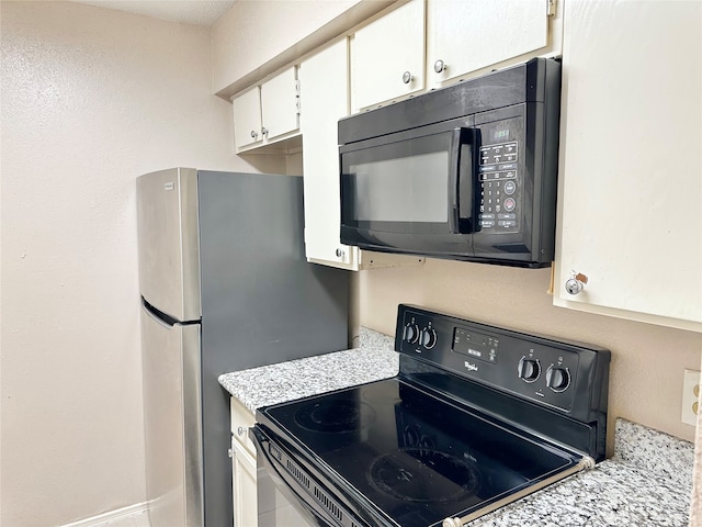 kitchen with white cabinets, light stone countertops, and black appliances