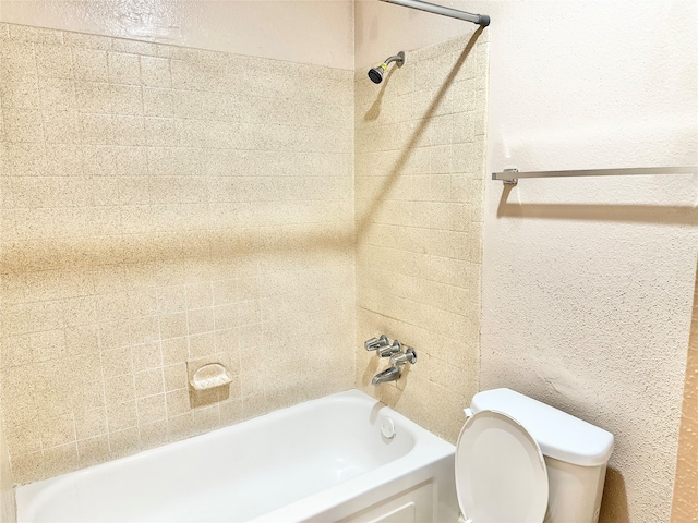 bathroom with tiled shower / bath combo and toilet