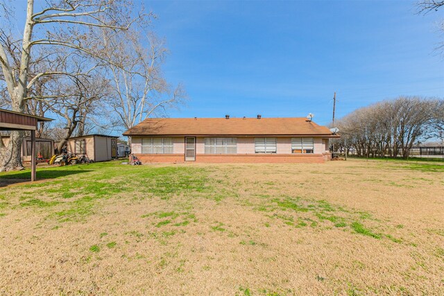 rear view of property featuring a yard and a storage unit