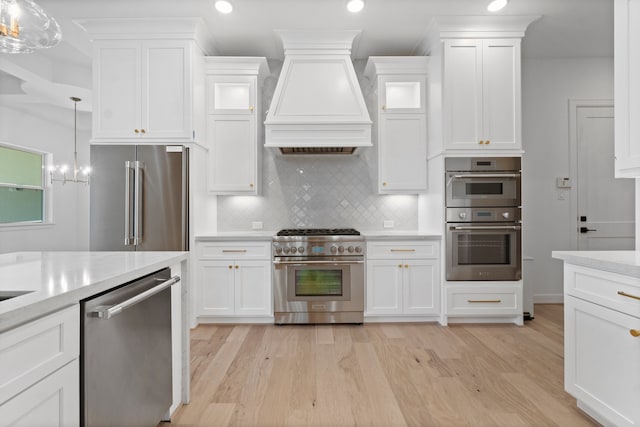 kitchen featuring white cabinets, custom exhaust hood, light hardwood / wood-style flooring, and high quality appliances