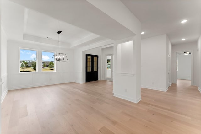 interior space with a raised ceiling, light hardwood / wood-style floors, and a notable chandelier