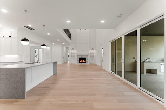 kitchen with white cabinetry, sink, pendant lighting, and light hardwood / wood-style flooring