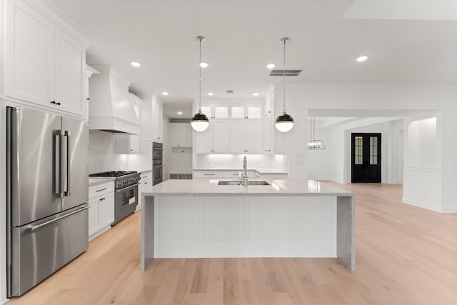 kitchen featuring white cabinetry, high quality appliances, sink, and a kitchen island with sink