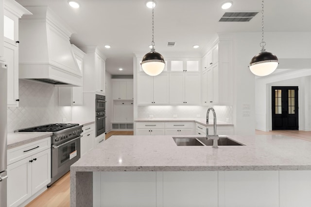 kitchen featuring high end stainless steel range, sink, custom exhaust hood, pendant lighting, and white cabinets