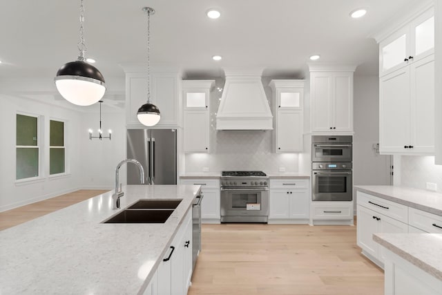 kitchen featuring sink, white cabinets, custom exhaust hood, high end appliances, and hanging light fixtures