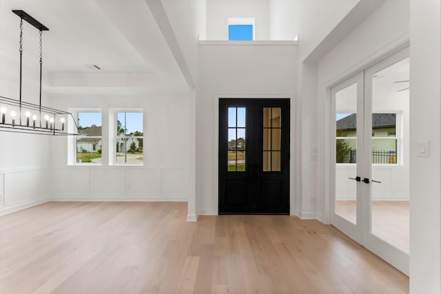 foyer entrance featuring light hardwood / wood-style floors, french doors, and a chandelier