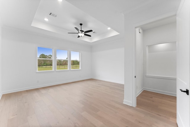 unfurnished room with ceiling fan, a raised ceiling, and light wood-type flooring