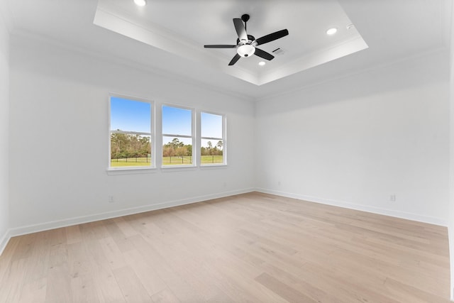 spare room featuring crown molding, a tray ceiling, and light hardwood / wood-style floors