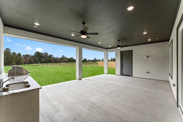 view of patio / terrace with ceiling fan, an outdoor kitchen, sink, and a rural view