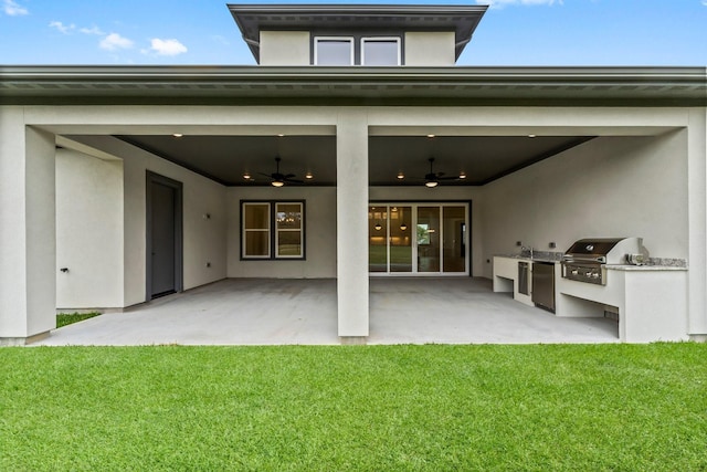 back of house with exterior kitchen, a lawn, ceiling fan, and a patio area