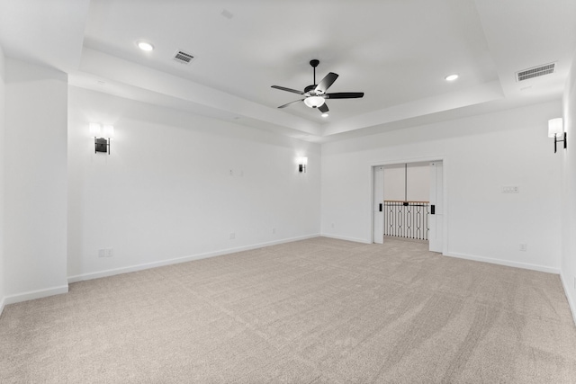 carpeted spare room featuring ceiling fan and a tray ceiling