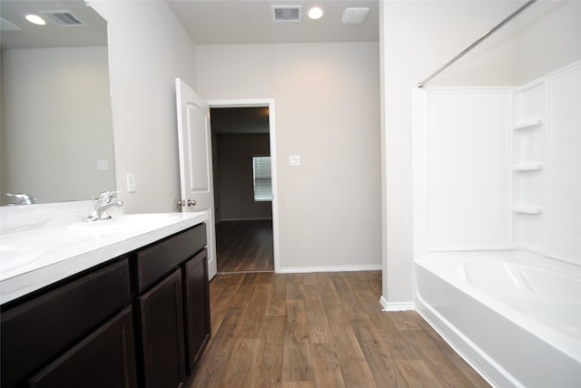 bathroom with hardwood / wood-style floors,  shower combination, and large vanity