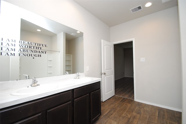 bathroom featuring double sink, oversized vanity, and wood-type flooring