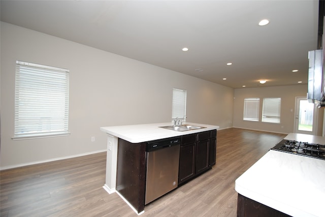 kitchen with light wood-type flooring, dishwasher, sink, and a kitchen island with sink