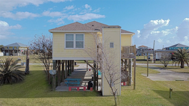 rear view of house featuring a balcony and a lawn