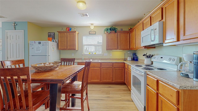 kitchen featuring white appliances, sink, and light wood-type flooring