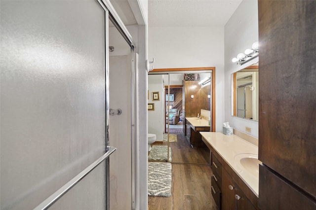 bathroom featuring toilet, vanity with extensive cabinet space, walk in shower, and wood-type flooring