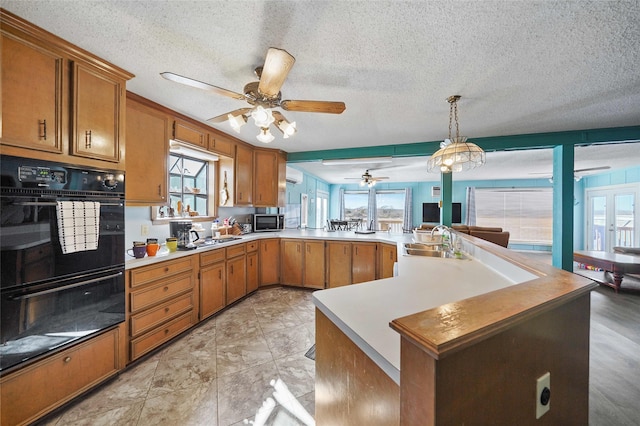 kitchen featuring double oven, light tile floors, ceiling fan, hanging light fixtures, and sink