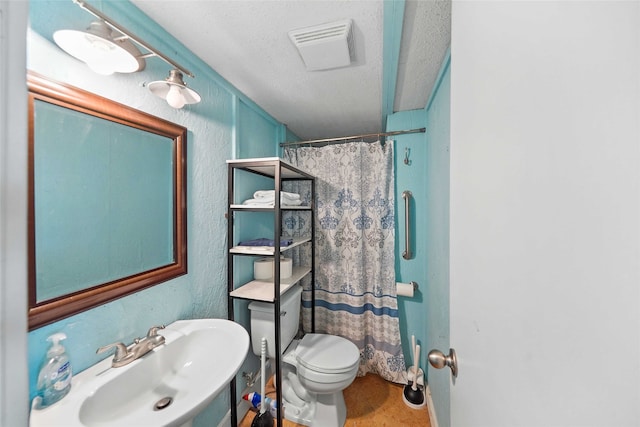 bathroom with toilet, tile floors, a textured ceiling, and sink