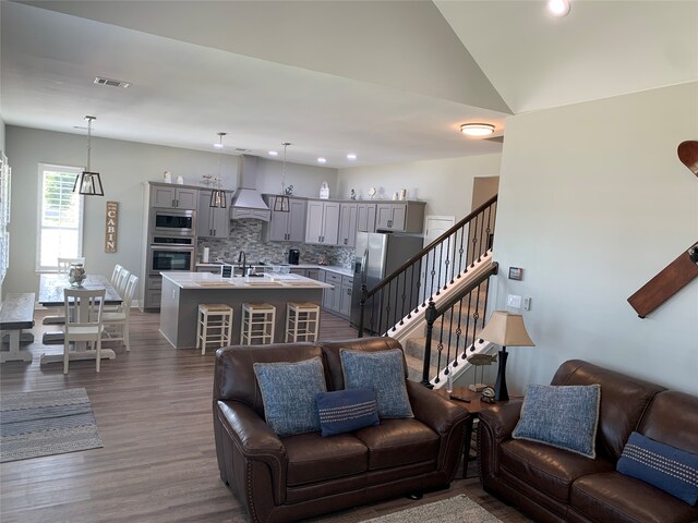 living room featuring vaulted ceiling, sink, and dark hardwood / wood-style flooring