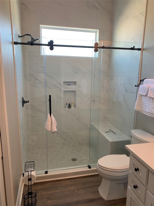 bathroom featuring vanity, toilet, a shower with shower door, and hardwood / wood-style flooring