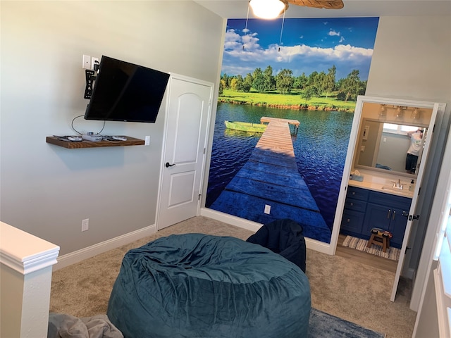 carpeted bedroom featuring a water view, ensuite bathroom, ceiling fan, and sink