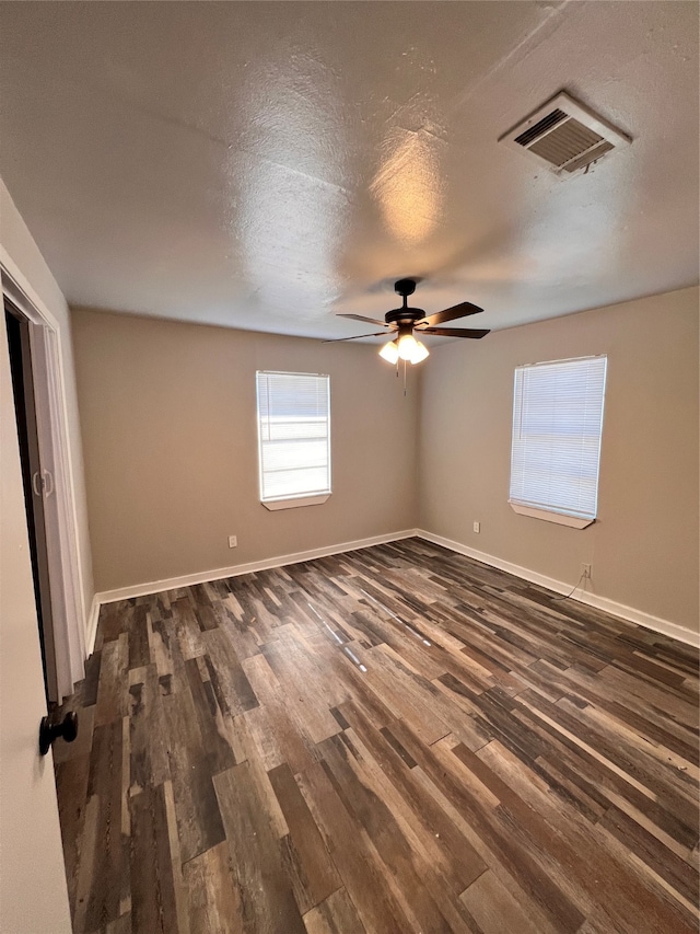 empty room with a textured ceiling, ceiling fan, and dark hardwood / wood-style floors