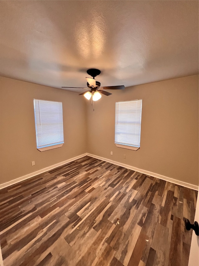 empty room with ceiling fan, dark wood-type flooring, and a textured ceiling