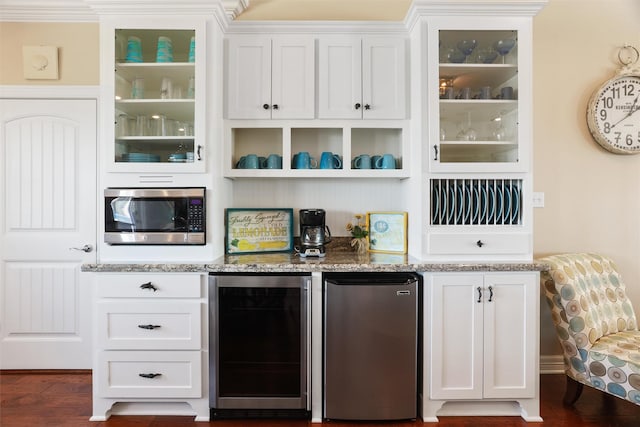 bar featuring beverage cooler, appliances with stainless steel finishes, dark wood-style floors, and a dry bar