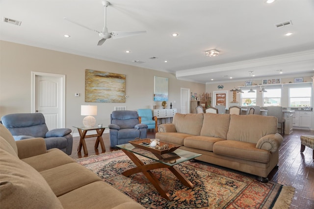 living area with dark wood-style floors, recessed lighting, visible vents, and ornamental molding